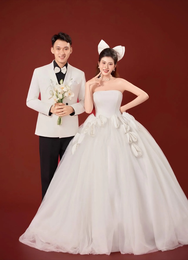 Ảnh cưới nền đỏ với váy trắng và vest trắng trong mẫu Lời Hẹn
